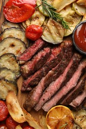 Photo of Delicious grilled beef with vegetables, lemon and spices on table, top view