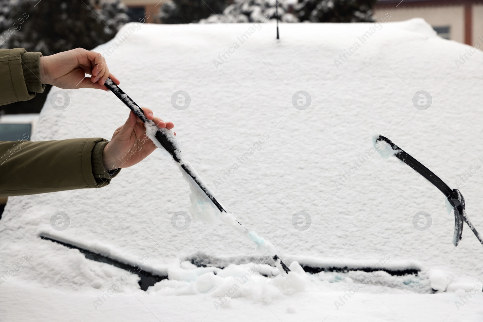 Photo of Woman cleaning wiper blade from snow outdoors, closeup