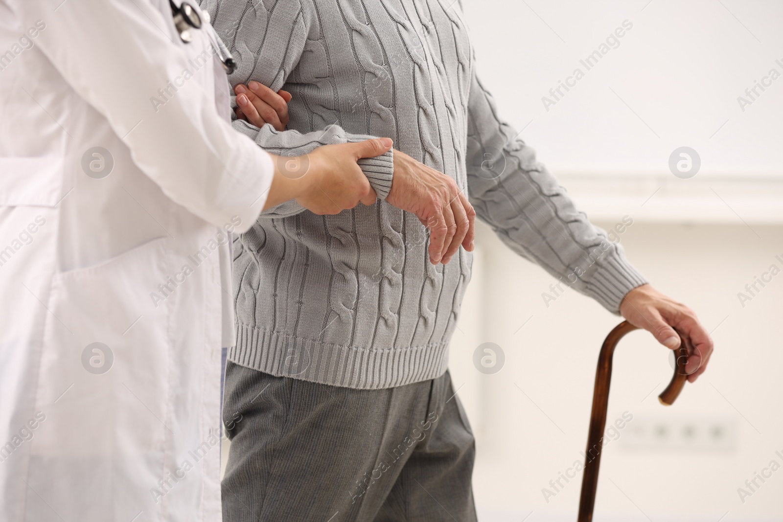 Photo of Nurse supporting elderly patient indoors, closeup view