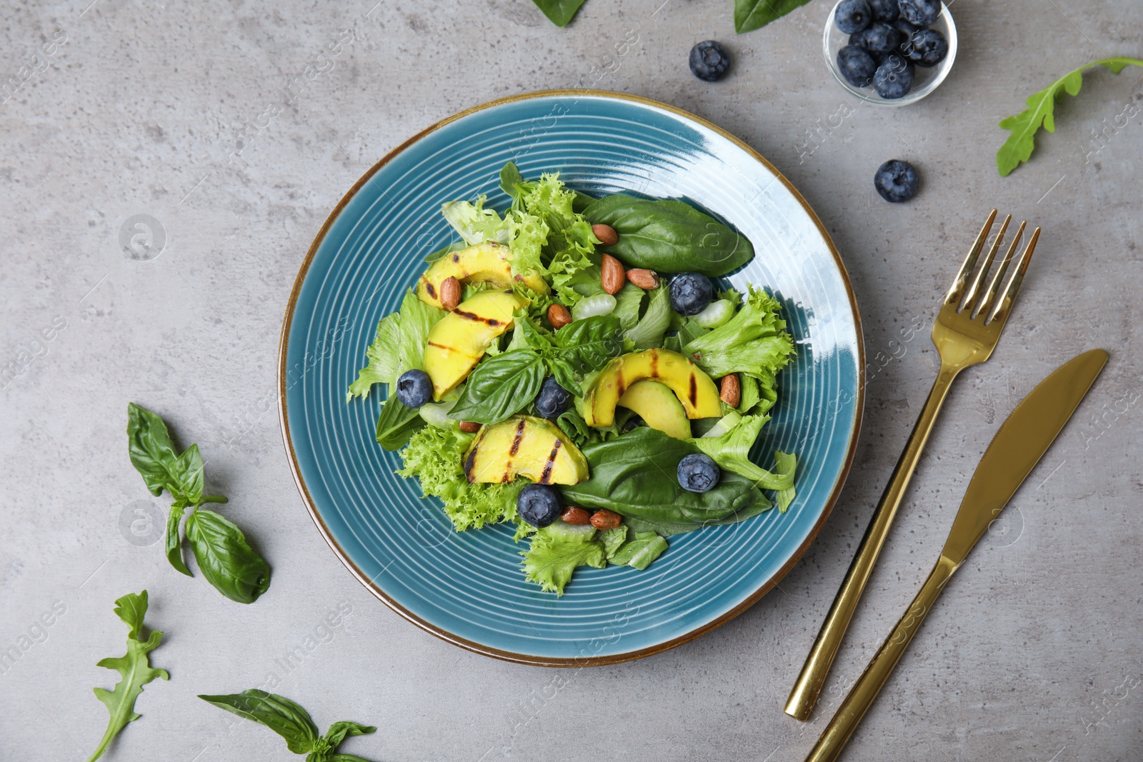 Photo of Delicious avocado salad with blueberries on grey table, flat lay