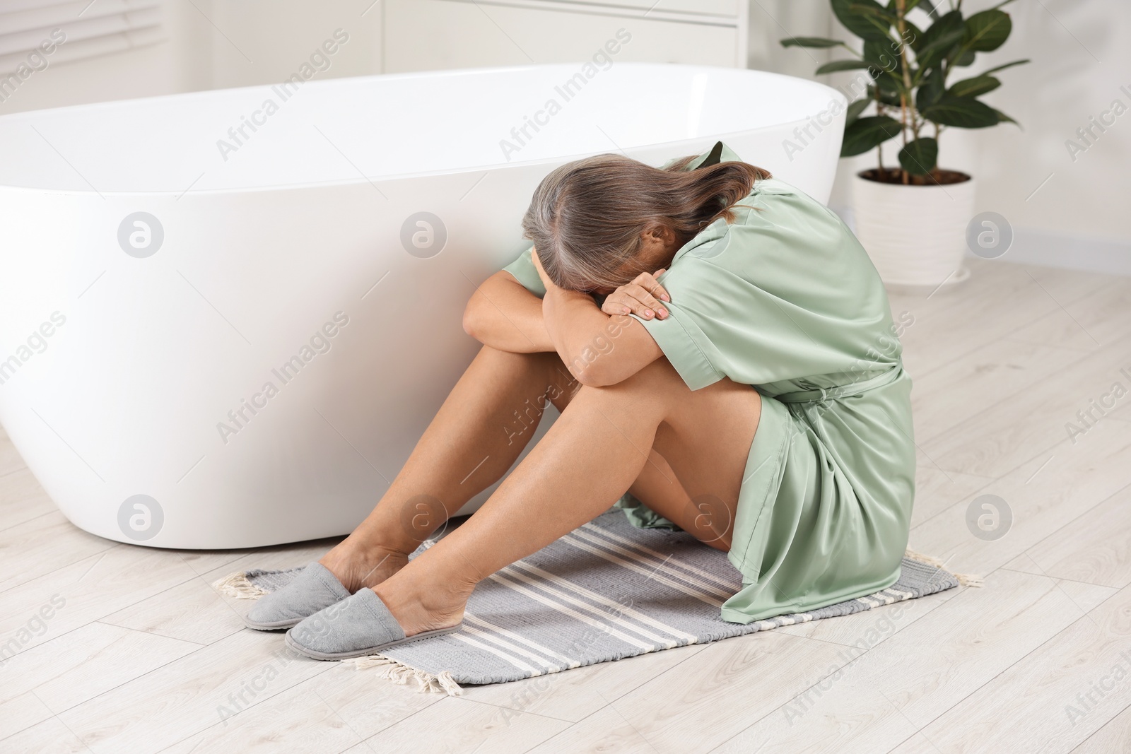 Photo of Menopause. Depressed woman near bath tub in bathroom