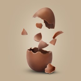 Exploded milk chocolate egg on dark beige background