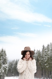 Photo of Young woman in warm sweater near snowy forest. Winter vacation