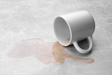 Photo of White mug with spilled liquid on light grey surface