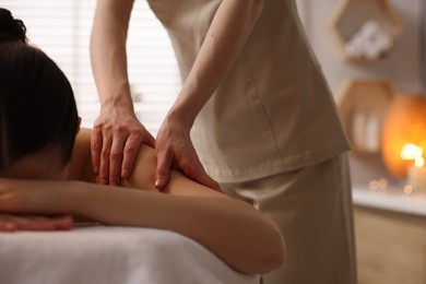 Woman receiving massage on couch in spa salon, closeup