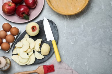 Photo of Cut fresh apple with knife on grey table, flat lay and space for text. Baking pie