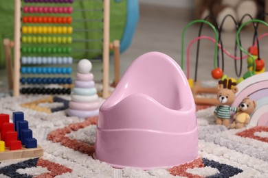 Pink baby potty and toys on carpet in room. Toilet training