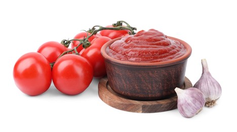 Photo of Organic ketchup in bowl, fresh tomatoes and garlic isolated on white. Tomato sauce