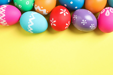 Photo of Colorful Easter eggs on yellow background, flat lay. Space for text