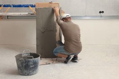 Photo of Worker spreading adhesive mix over tile with spatula