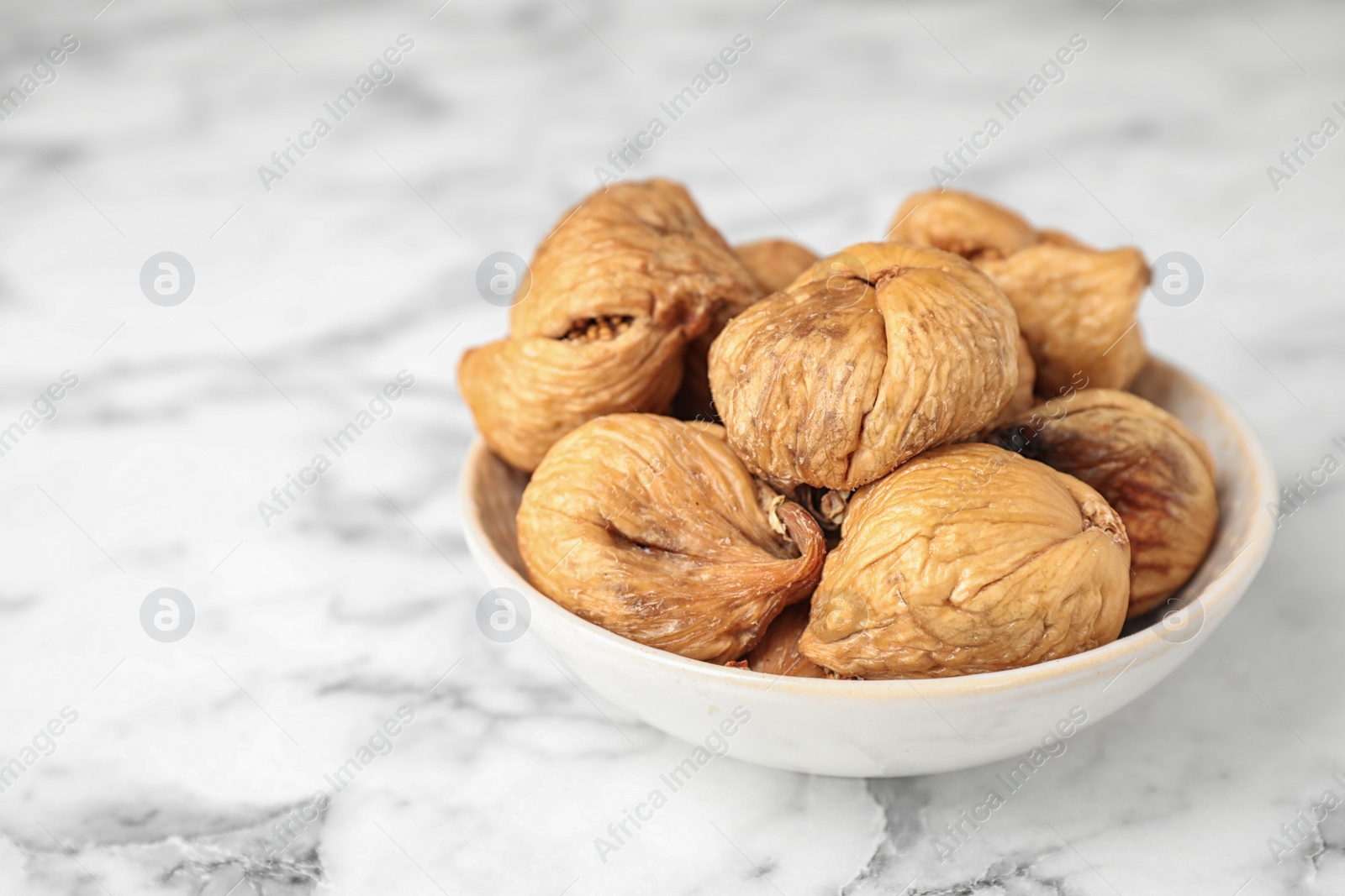 Photo of Bowl of tasty dried figs on marble table, closeup. Space for text