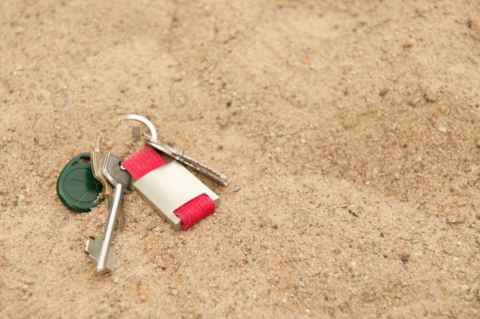 Photo of Keys on sand, space for text. Lost and found