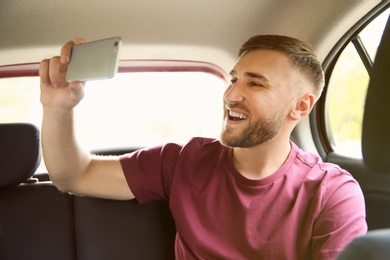 Happy young man taking selfie in car