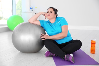 Photo of Overweight woman sitting on mat in gym