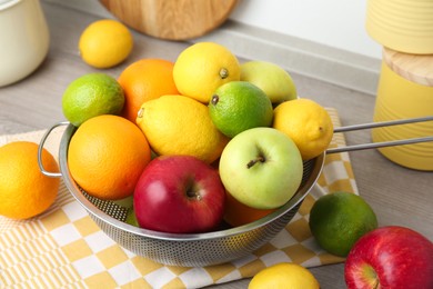 Photo of Metal colander with different fruits on table, closeup