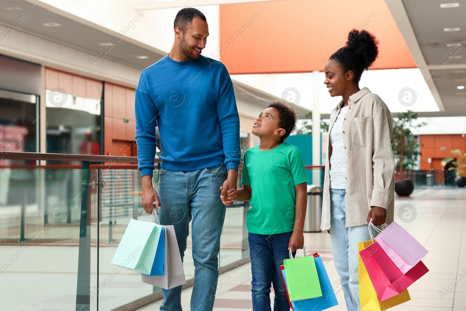 Photo of Family shopping. Happy parents and son with colorful bags in mall