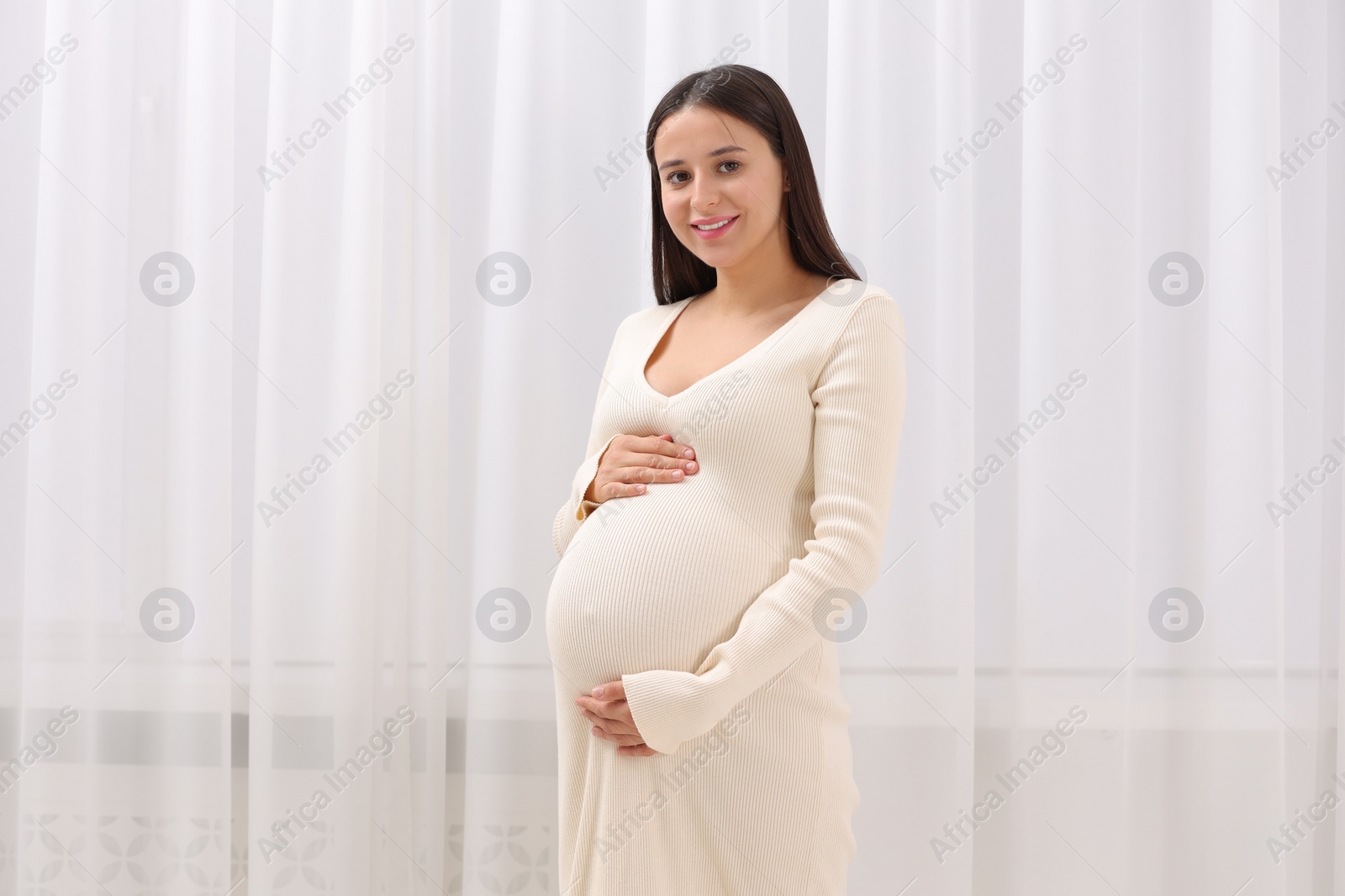 Photo of Beautiful pregnant woman in white dress indoors