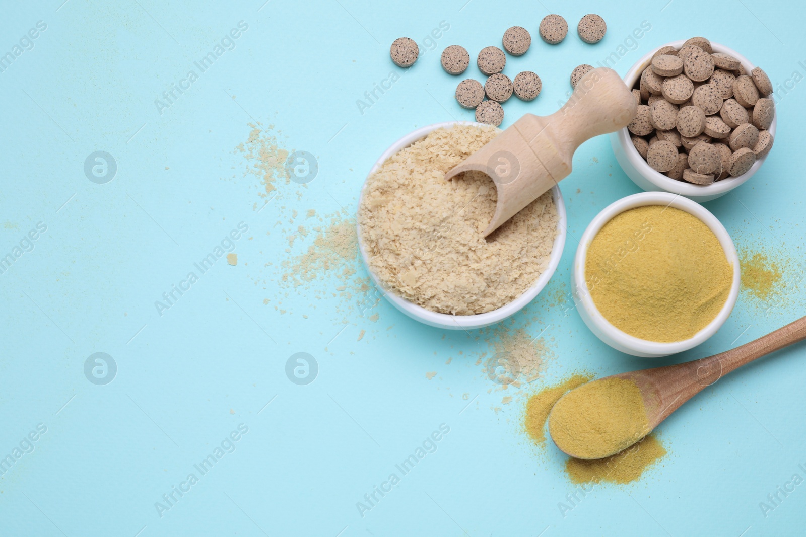 Photo of Beer yeast powder, flakes and pills on light blue background, flat lay. Space for text