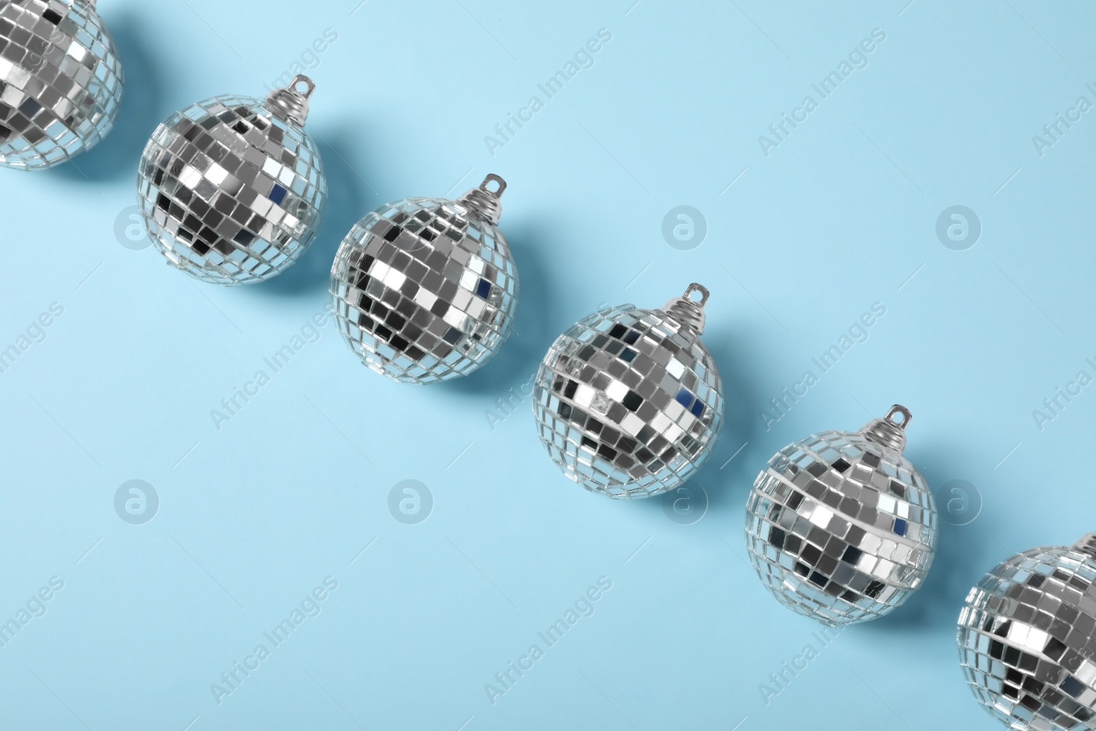 Photo of Shiny disco balls on light blue background, flat lay