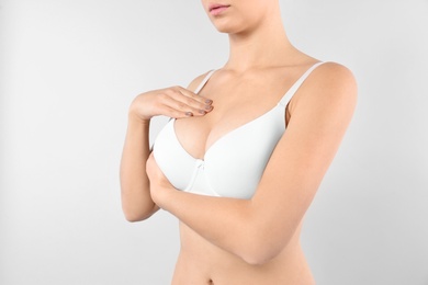 Woman checking her breast on white background, closeup