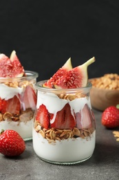 Photo of Jars of tasty homemade granola dessert on grey table. Healthy breakfast