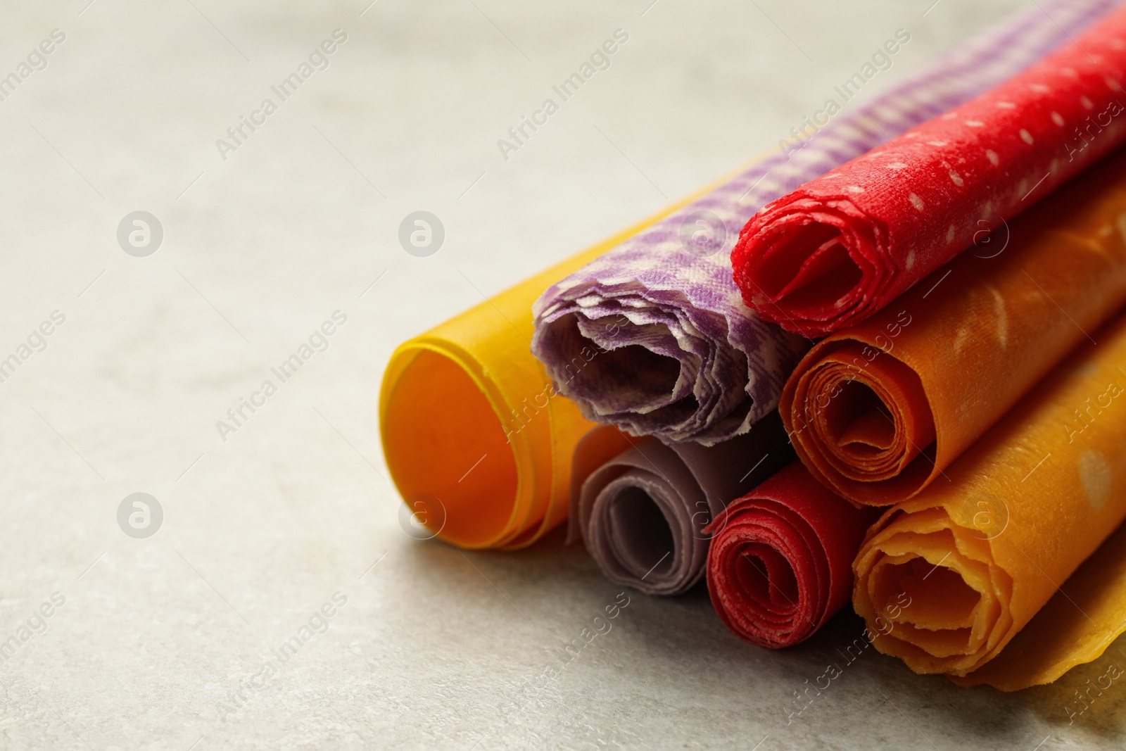 Photo of Colorful beeswax food wraps on light table, closeup. Space for text