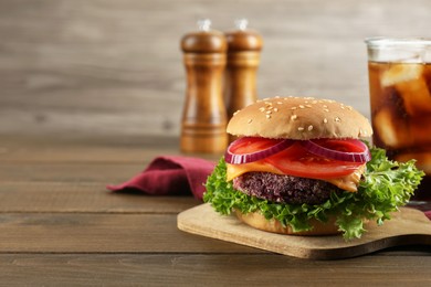 Photo of Tasty vegetarian burger with beet patty served on wooden table. Space for text