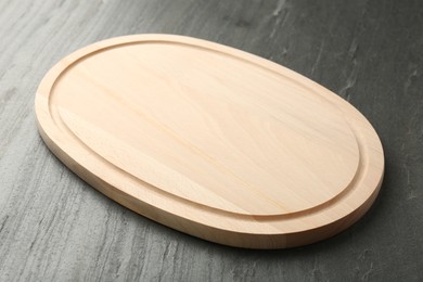 Photo of One wooden cutting board on dark grey table