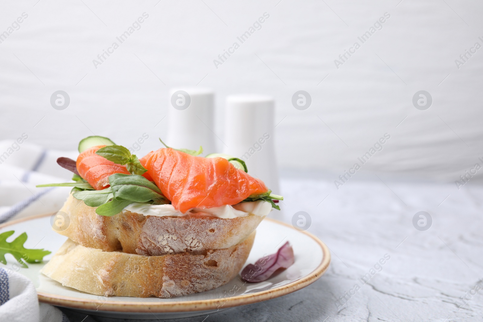 Photo of Tasty bruschetta with salmon, cucumbers and herbs on white textured table, closeup. Space for text