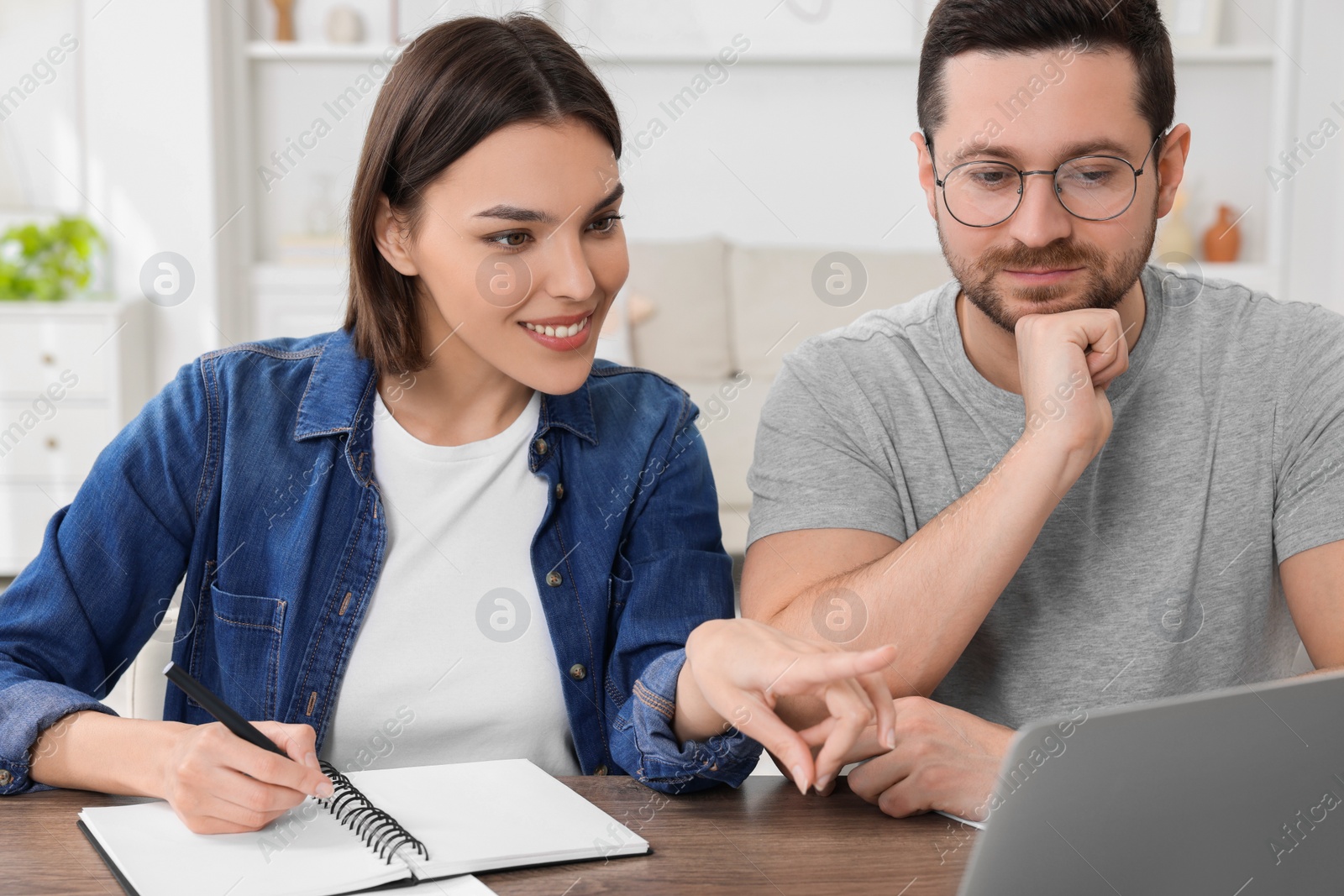 Photo of Young couple with papers discussing pension plan at wooden table indoors