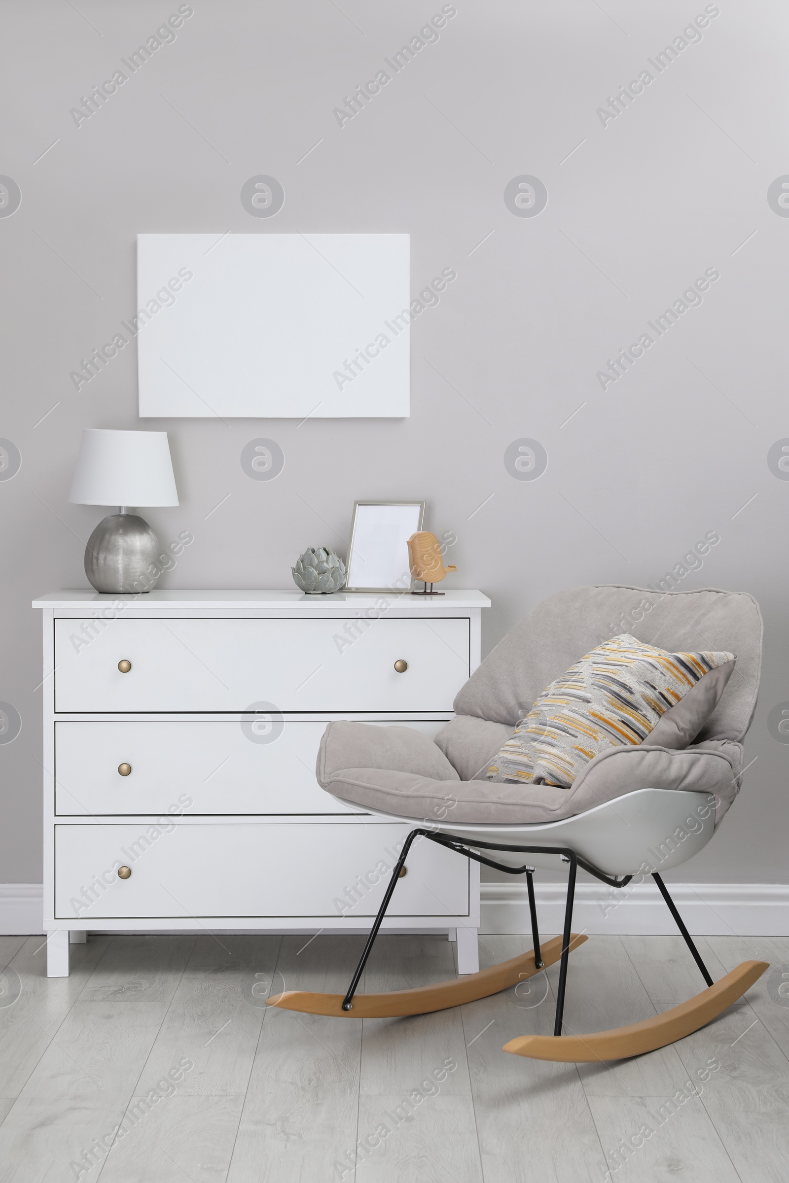 Photo of Blank canvas on wall over chest of drawers with decor in room. Space for design