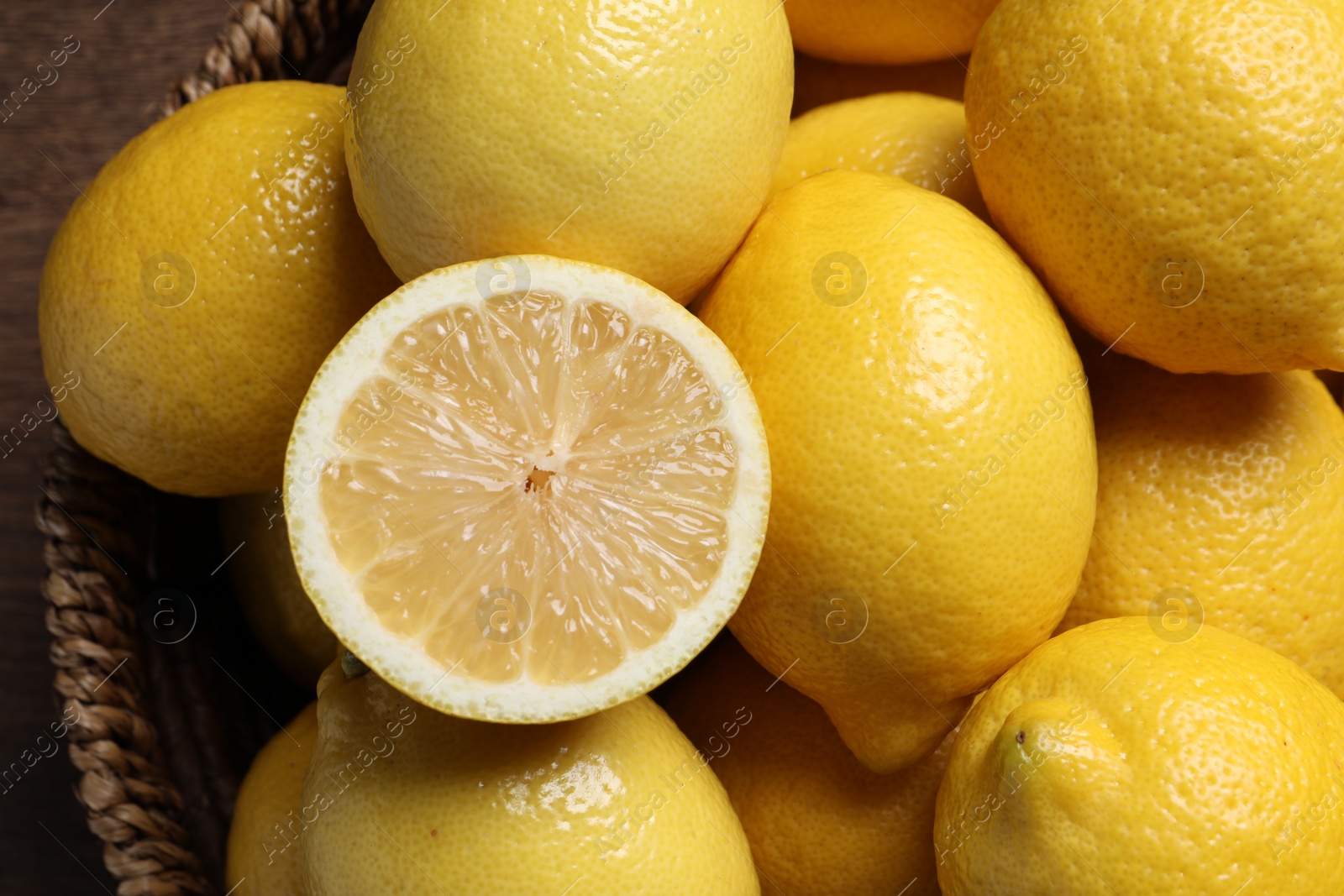 Photo of Fresh lemons in wicker basket on table, closeup