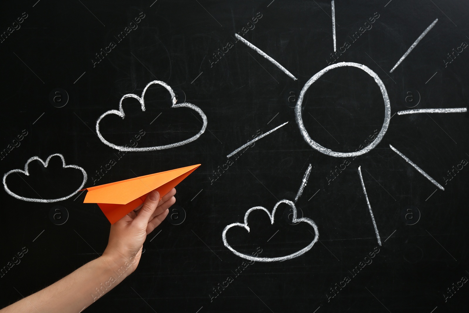 Photo of Woman holding paper plane near blackboard, closeup