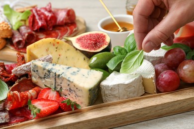 Photo of Woman taking basil from board with different appetizers, closeup