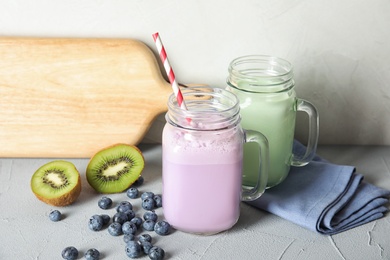 Photo of Mason jars with delicious milk shakes and ingredients on table