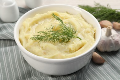 Bowl of tasty mashed potato with garlic and dill on table, closeup