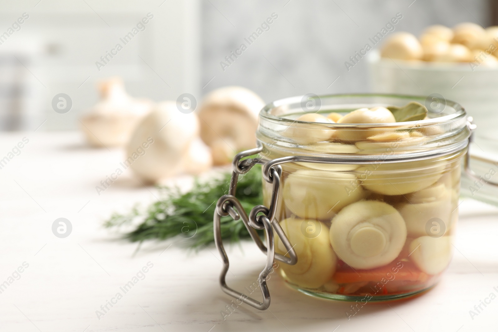 Photo of Jar with marinated mushrooms on white wooden table, closeup. Space for text