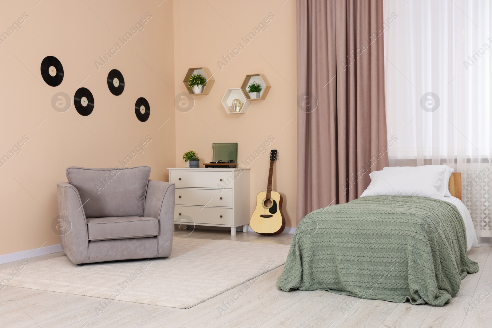 Photo of Comfortable bed, chest of drawers and armchair in bedroom. Interior design