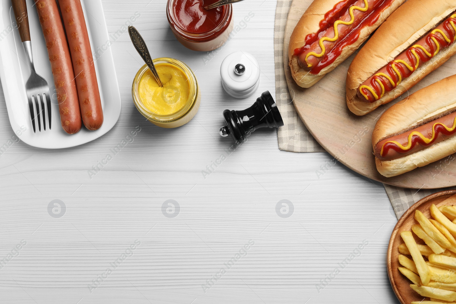 Photo of Fresh delicious hot dogs with sauces served on white wooden table, flat lay. Space for text