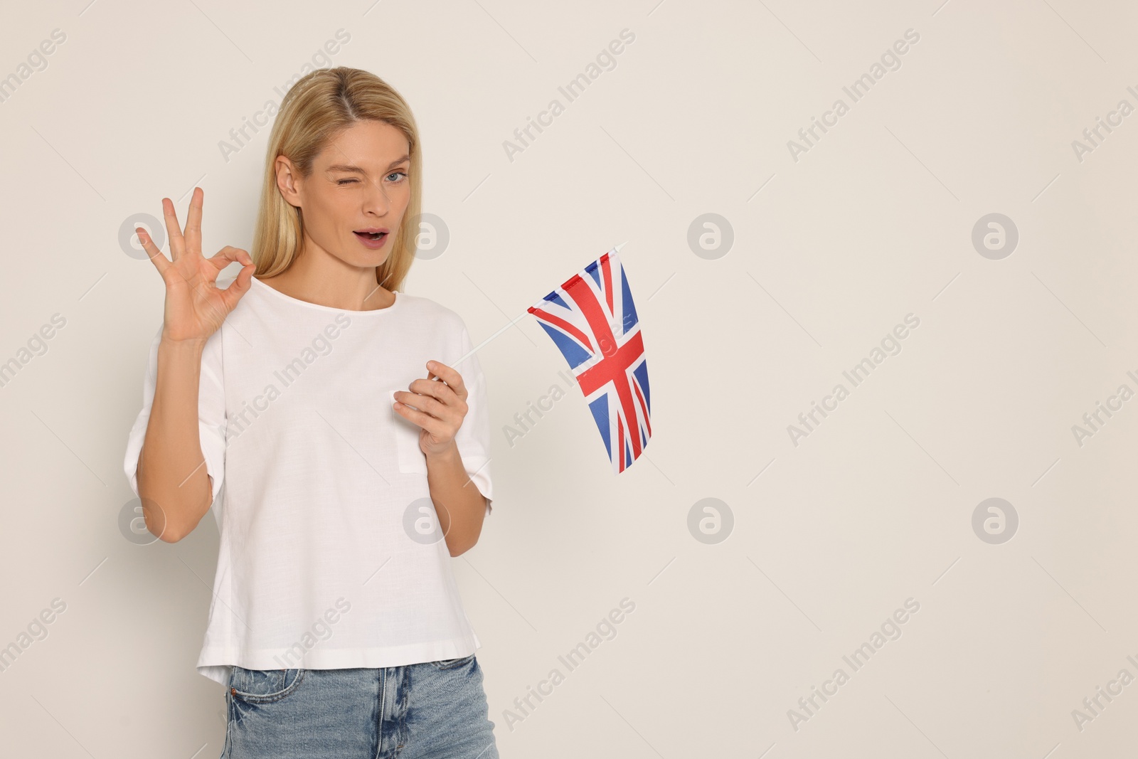 Photo of Woman with flag of United Kingdom showing ok gesture on white background, space for text