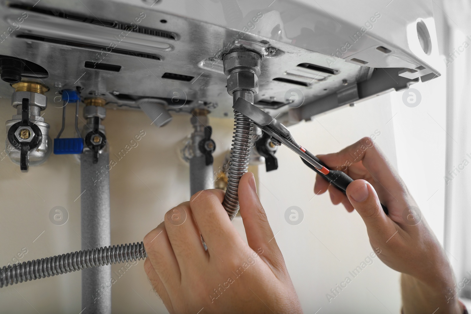 Photo of Man repairing gas boiler with waterpump plier, closeup