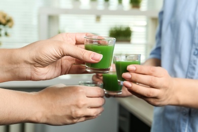 Photo of Women with shot glasses of wheat grass juice indoors, closeup