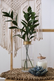 Photo of Vase with green branches, candle and decorative succulent on table indoors. Interior elements