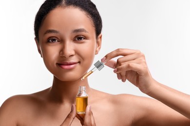 Beautiful woman with bottle of serum and dropper on white background