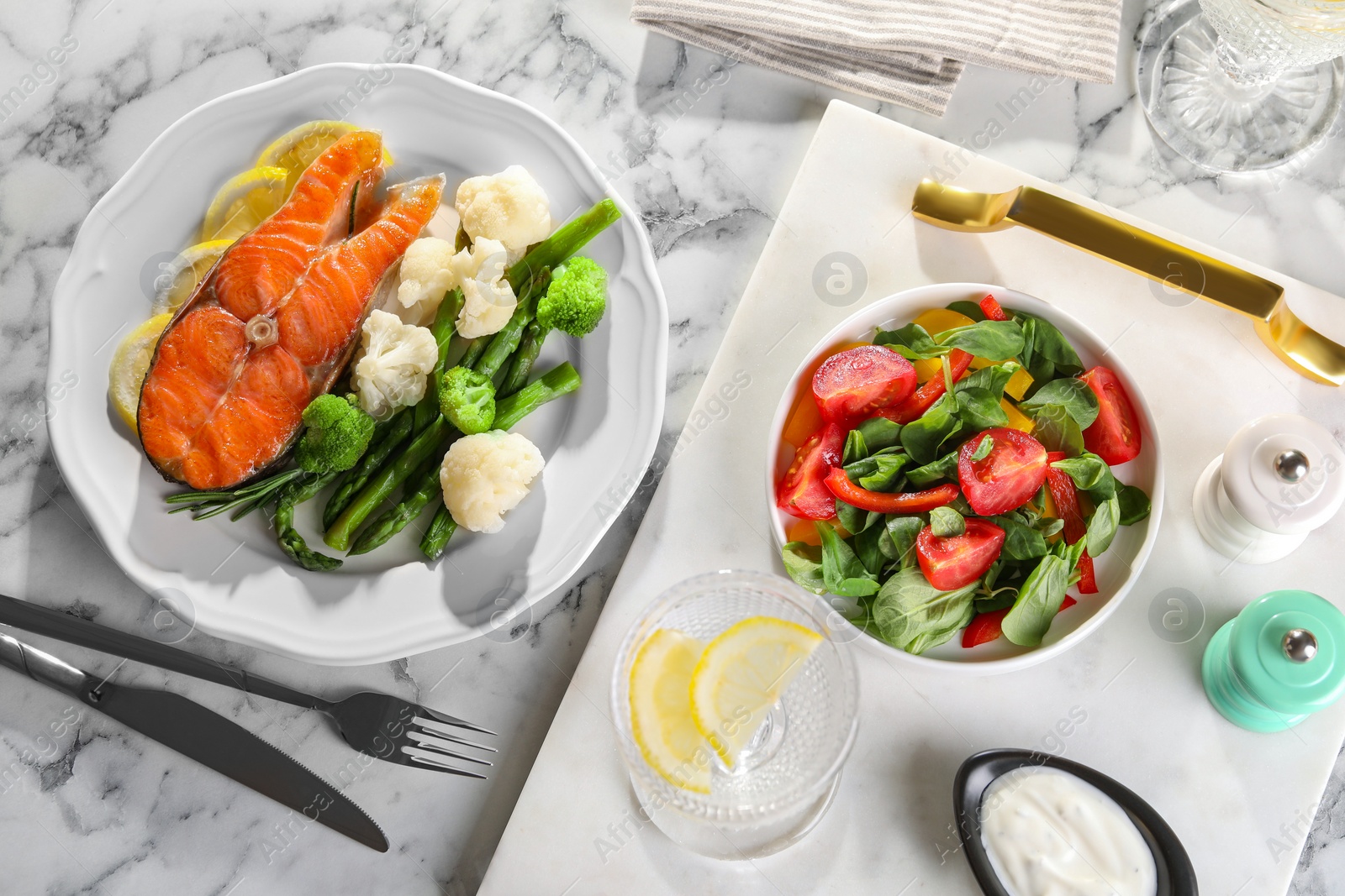 Photo of Healthy meal. Tasty grilled salmon with vegetables and lemon served on white marble table, flat lay