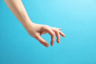 Photo of Woman holding something in hand on light blue background, closeup