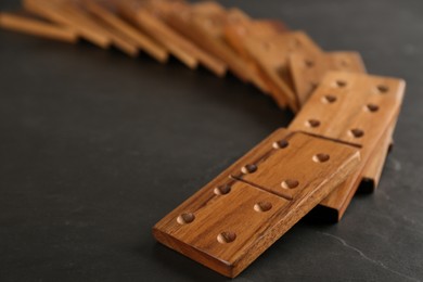 Photo of Fallen wooden domino tiles on dark grey table, closeup