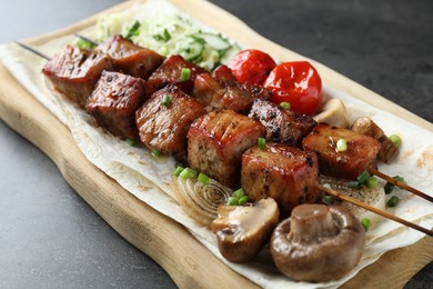 Photo of Delicious shish kebabs with vegetables and lavash on grey table, closeup