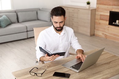 Photo of Handsome young man working at table in home office