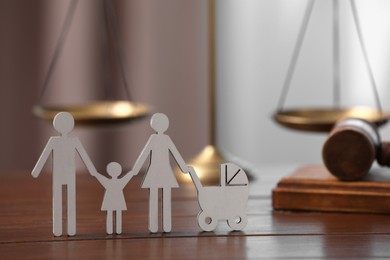 Photo of Family law. Figure of parents with children, scales and gavel on wooden table, space for text